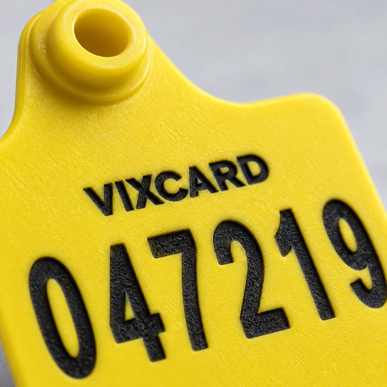 Detalhe macro da numeração gravada a laser no brinco bovino Vixcard, com sulco em relevo que não desbota